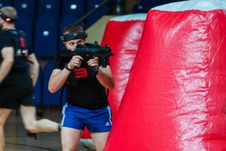 Боец LASERWAR с автоматом держит оборону у красного укрытия.